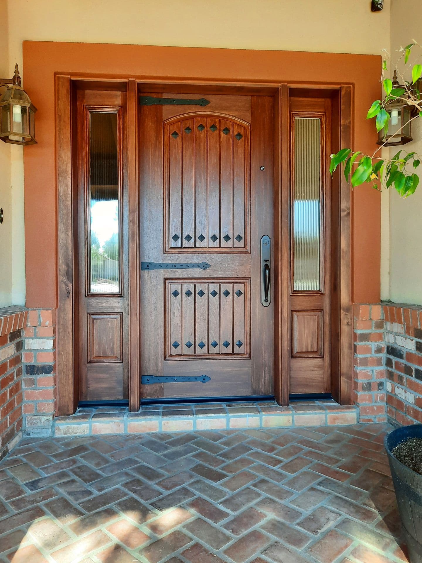 Wood entry door with sidelights on a brick porch