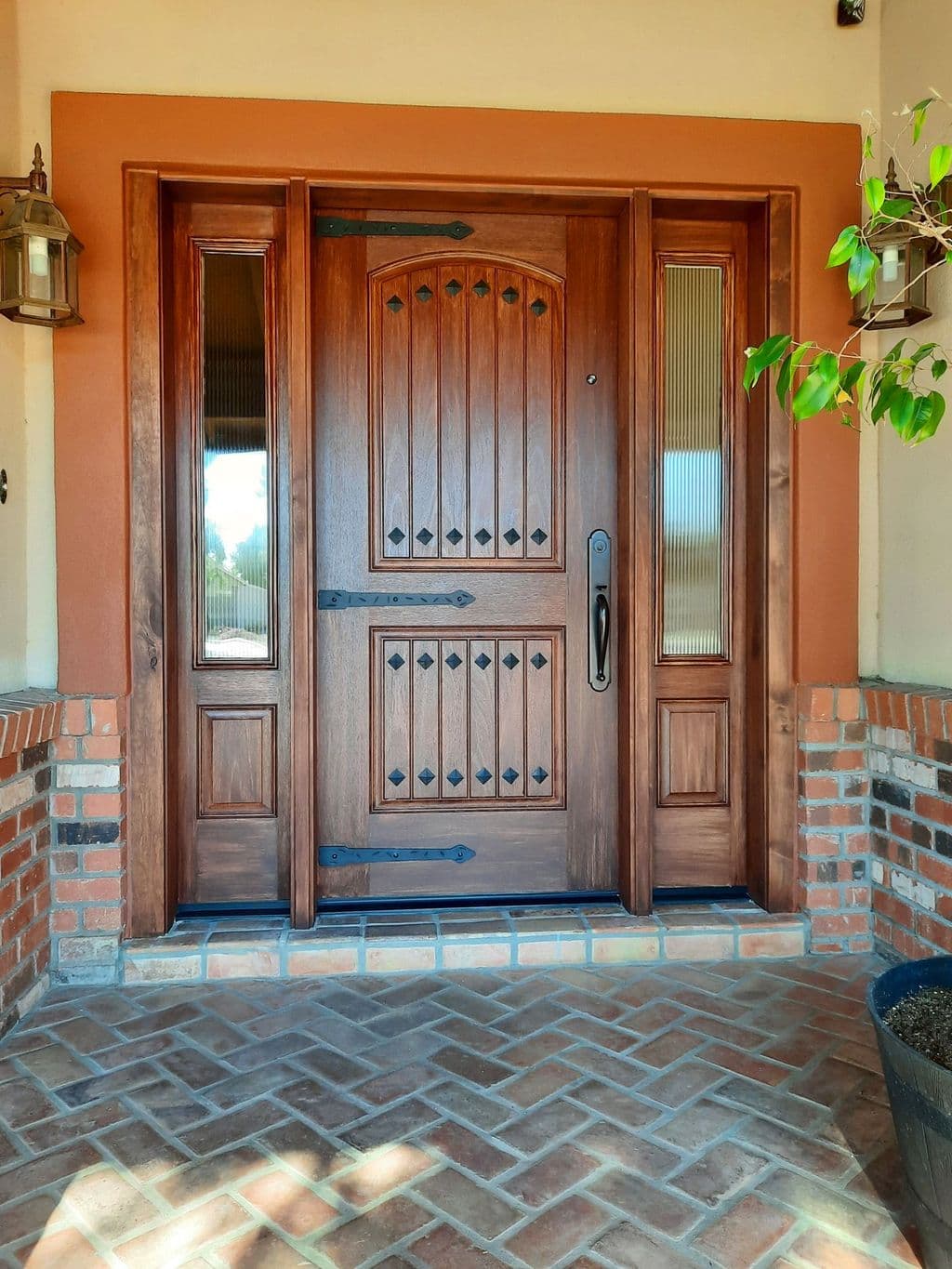 Wood entry door with sidelights on a brick porch