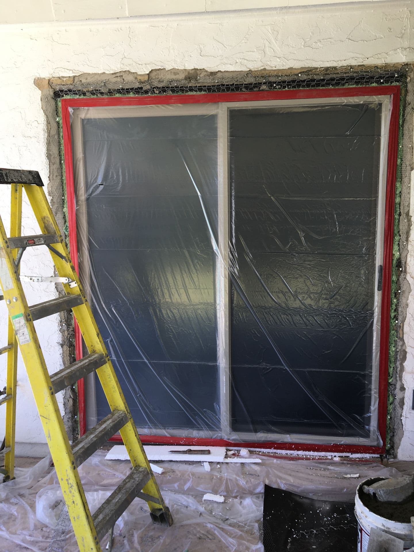 Sliding door masked off with plastic and tape before stucco and paint work