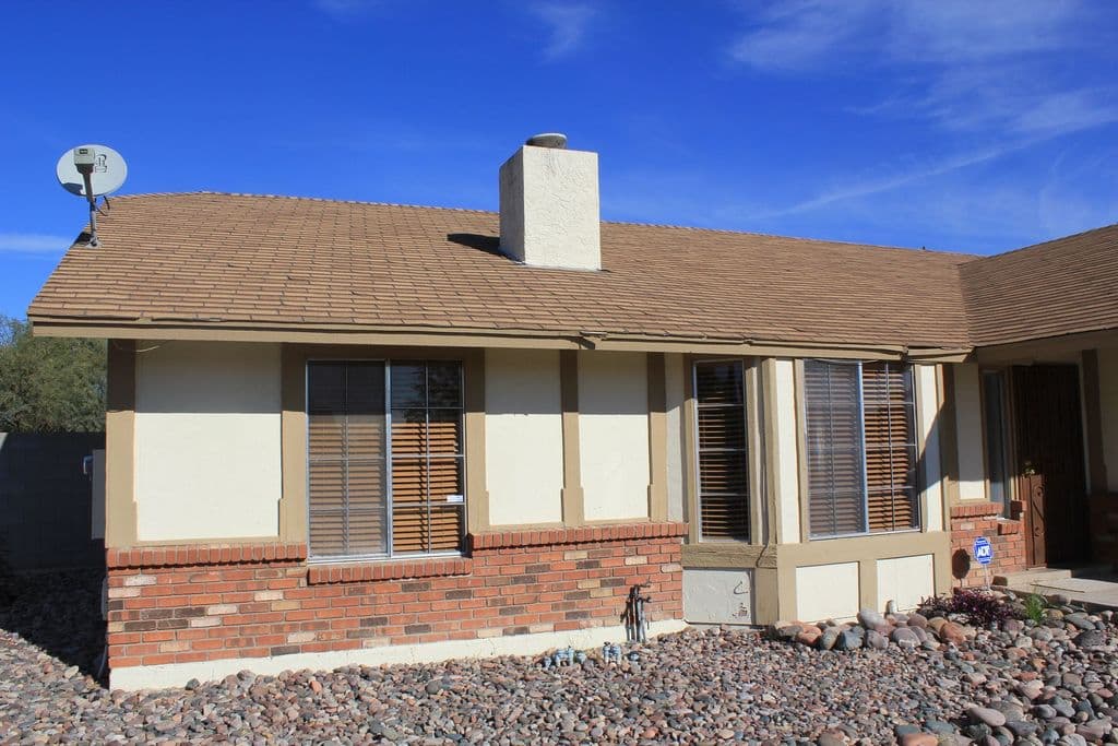 Single-story home with siding panels above a brick wainscot