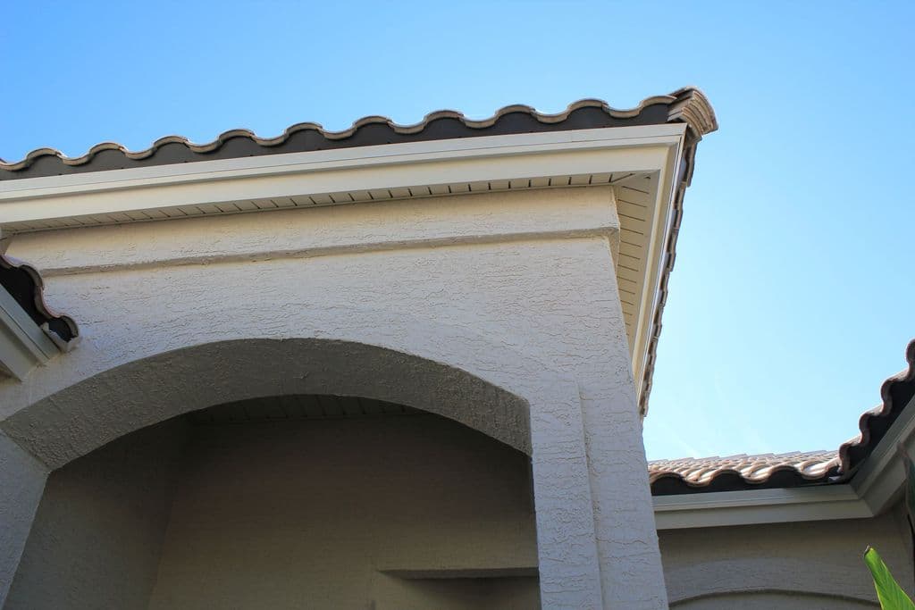 Finished soffit and fascia along a tile roof above an arched entry
