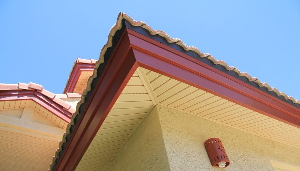 Red tile roof gables with new terracotta aluminum fascia and drip edge, almond vinyl soffit over tan stucco